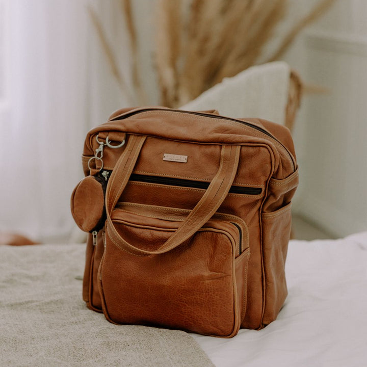 Brown leather bag on a bed with a blurred background