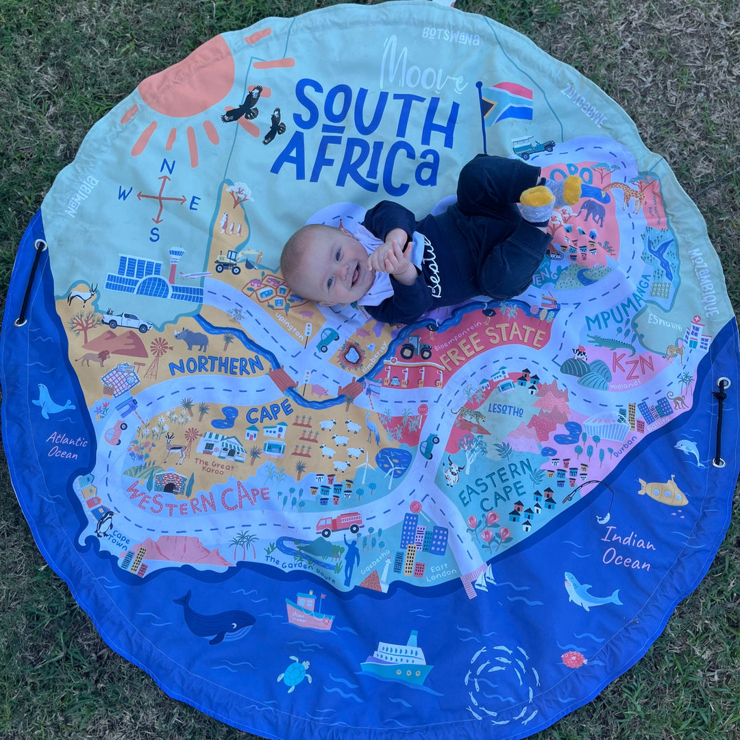 Child lying on a South Africa-themed play mat outdoors