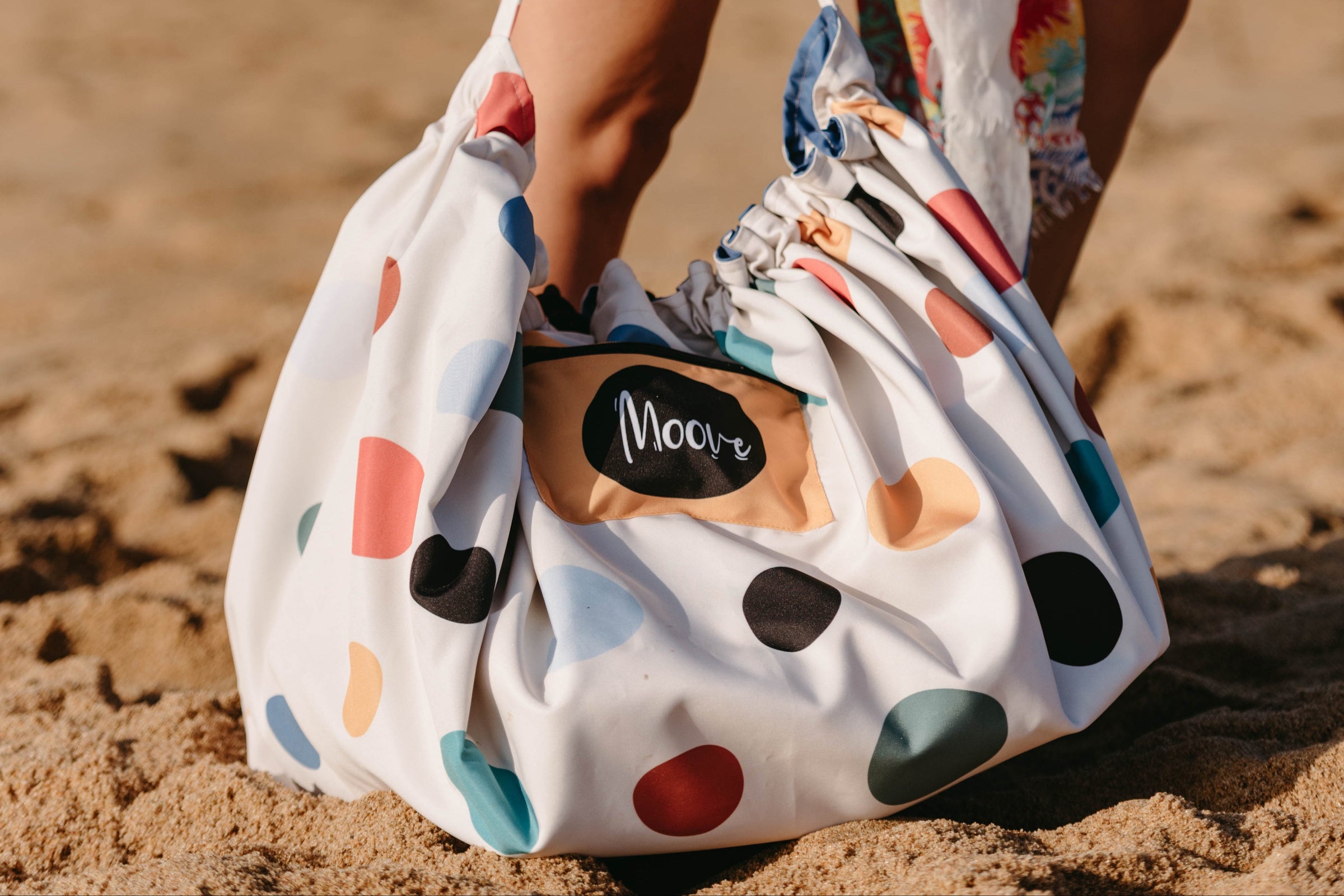 Person holding a polka dot bag on a beach