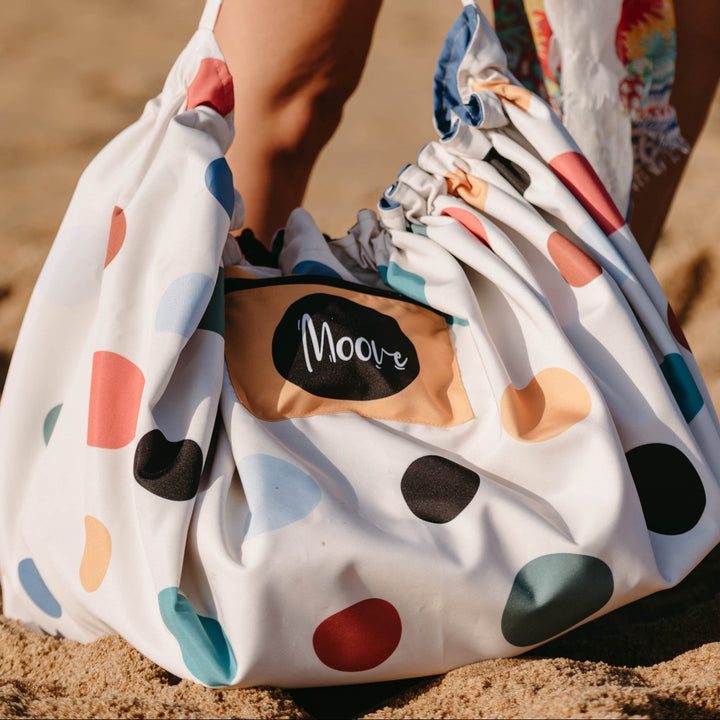 Person holding a polka dot bag on a beach