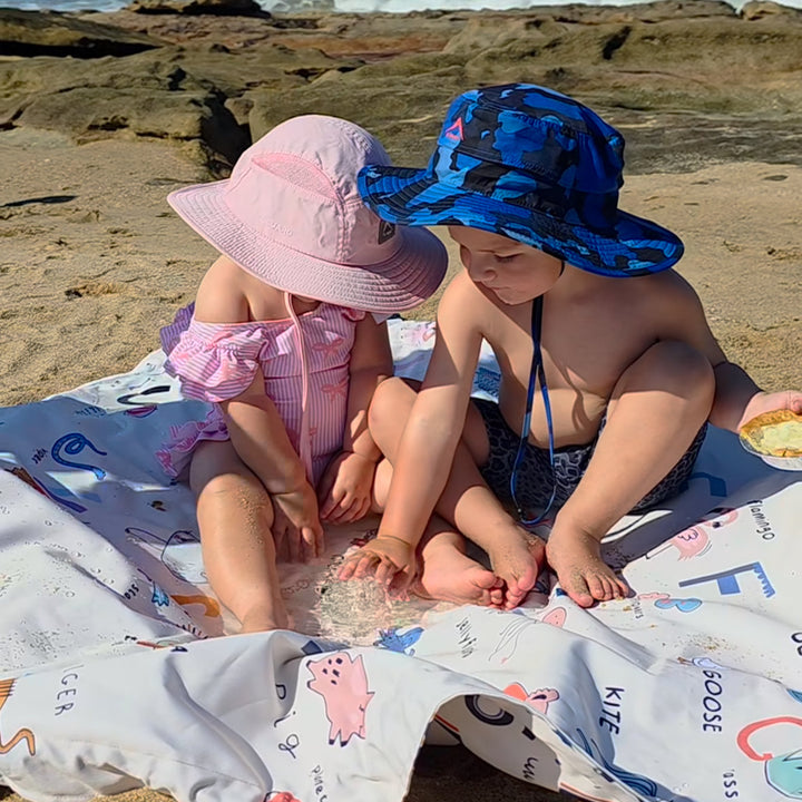 Two children sitting on a moove bag by the ocean