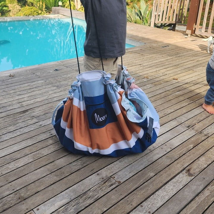 Child playing with a bag on a wooden deck by a pool